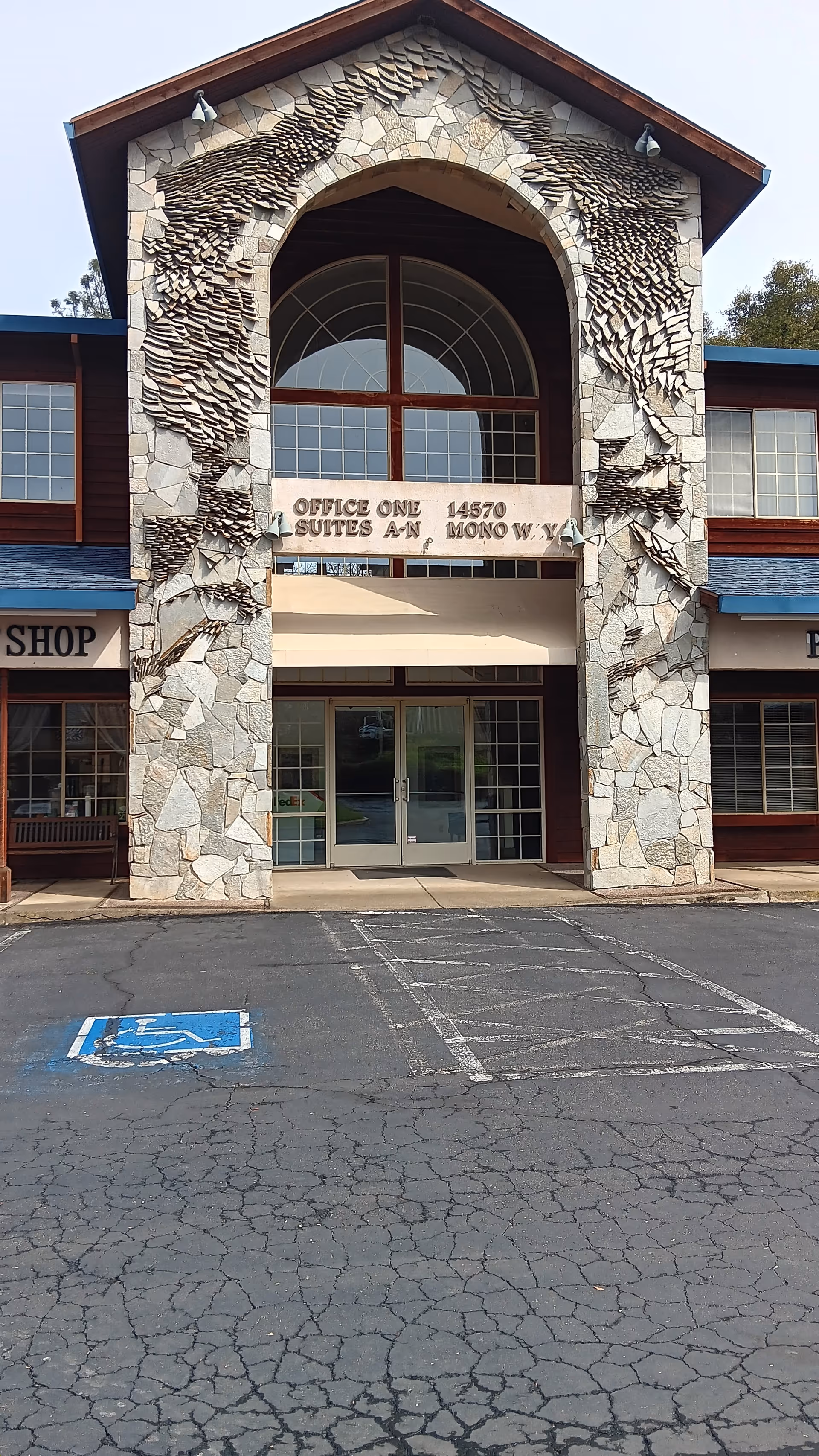 Stone-framed building entrance with arched window, glass doors, and a handicapped parking space.