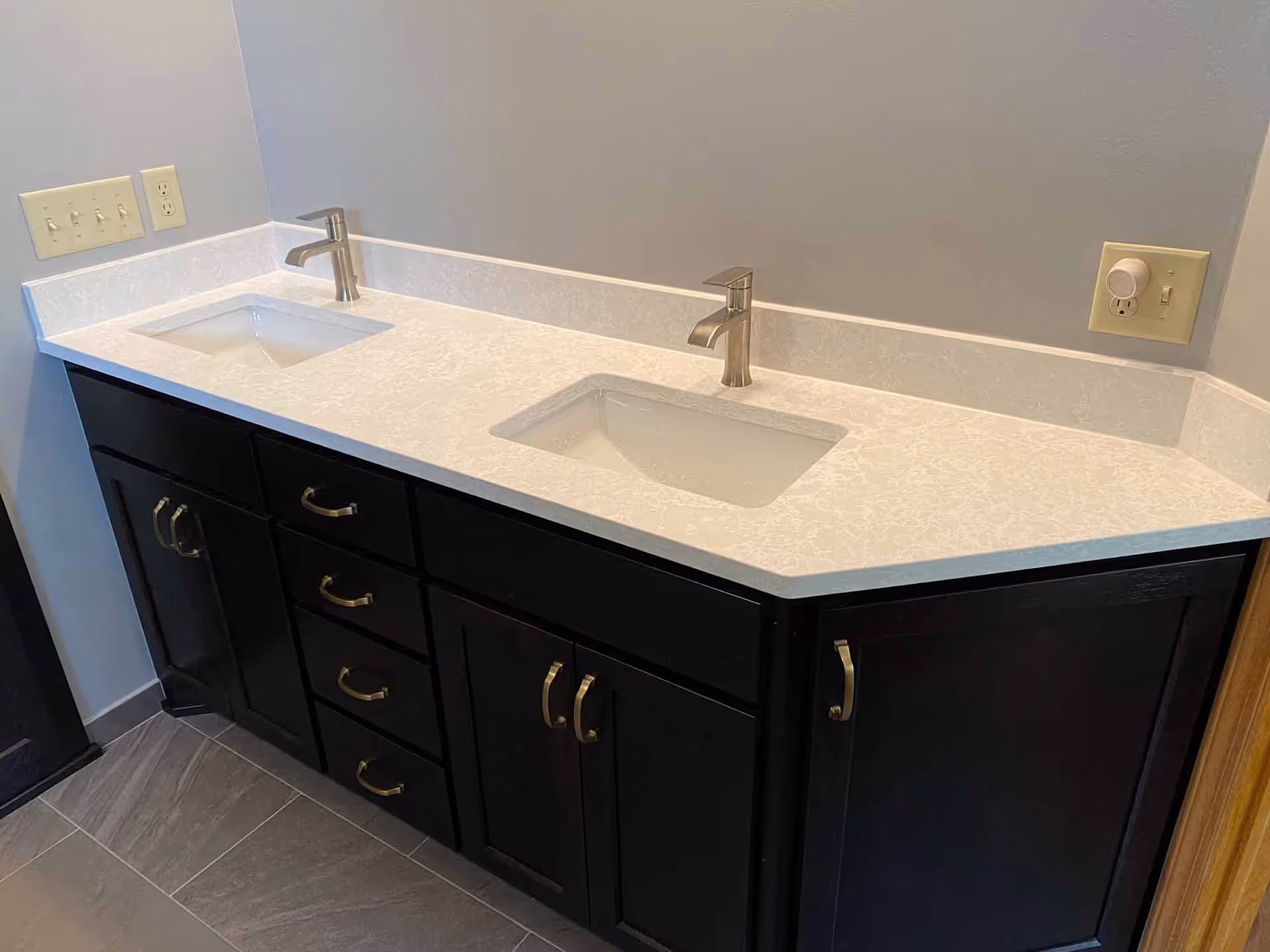 Double-sink bathroom vanity with dark cabinets and light countertop.