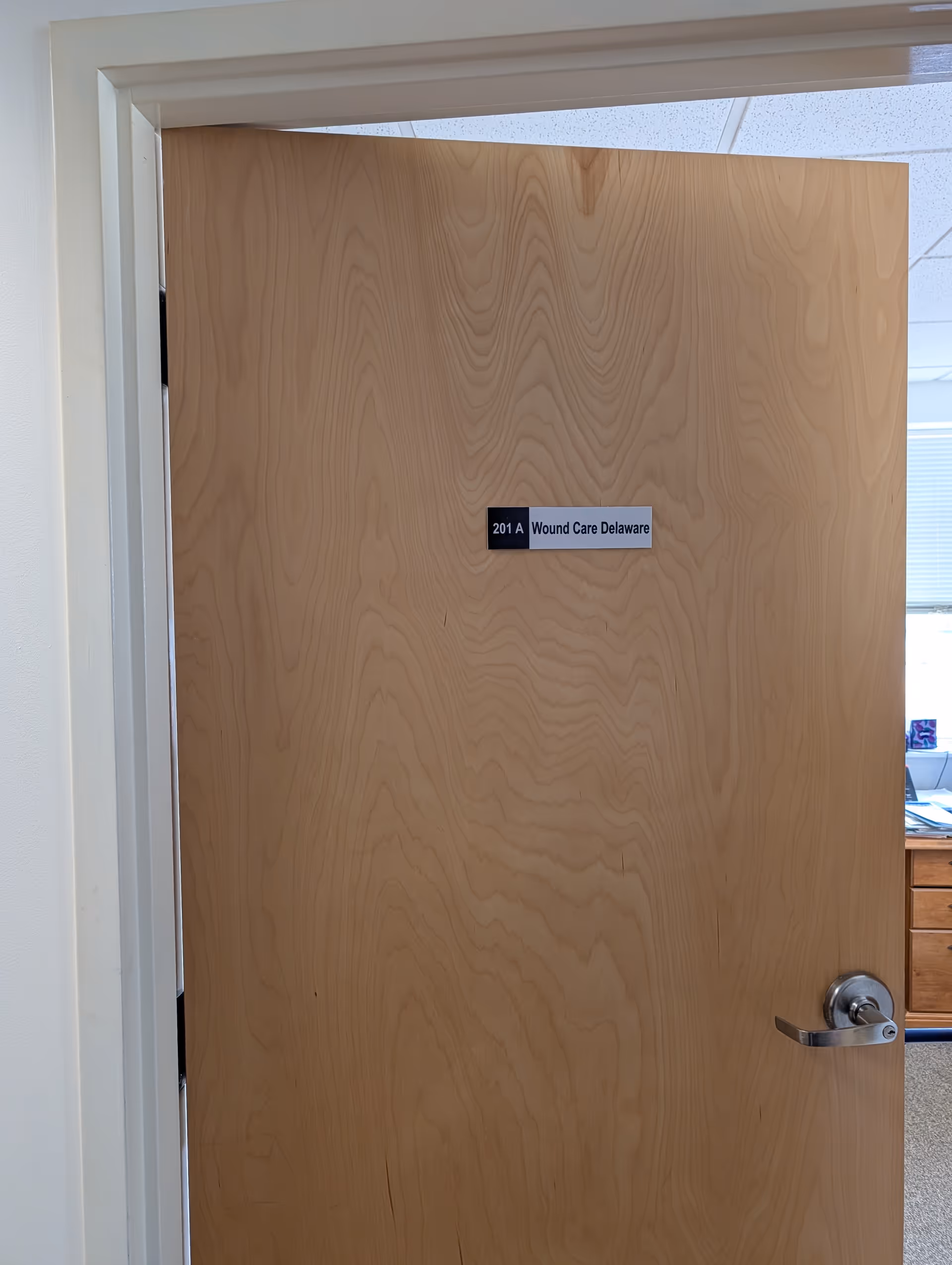 Wooden interior door with room label Wound Care Delaware and metal lever handle.