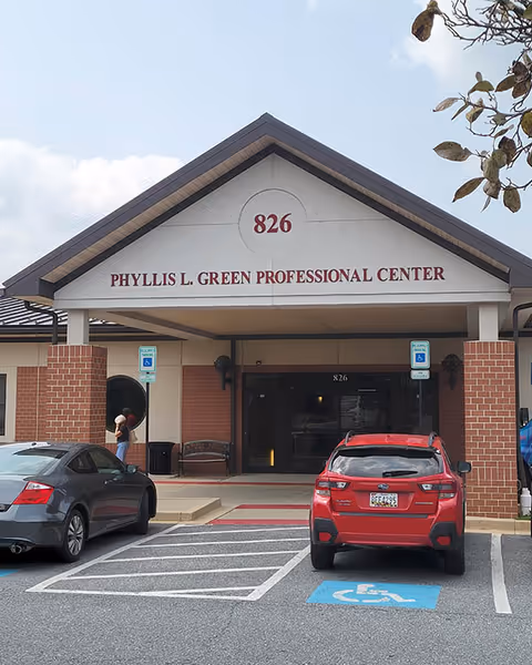 Front view of a building entrance with parked cars and handicap spaces.