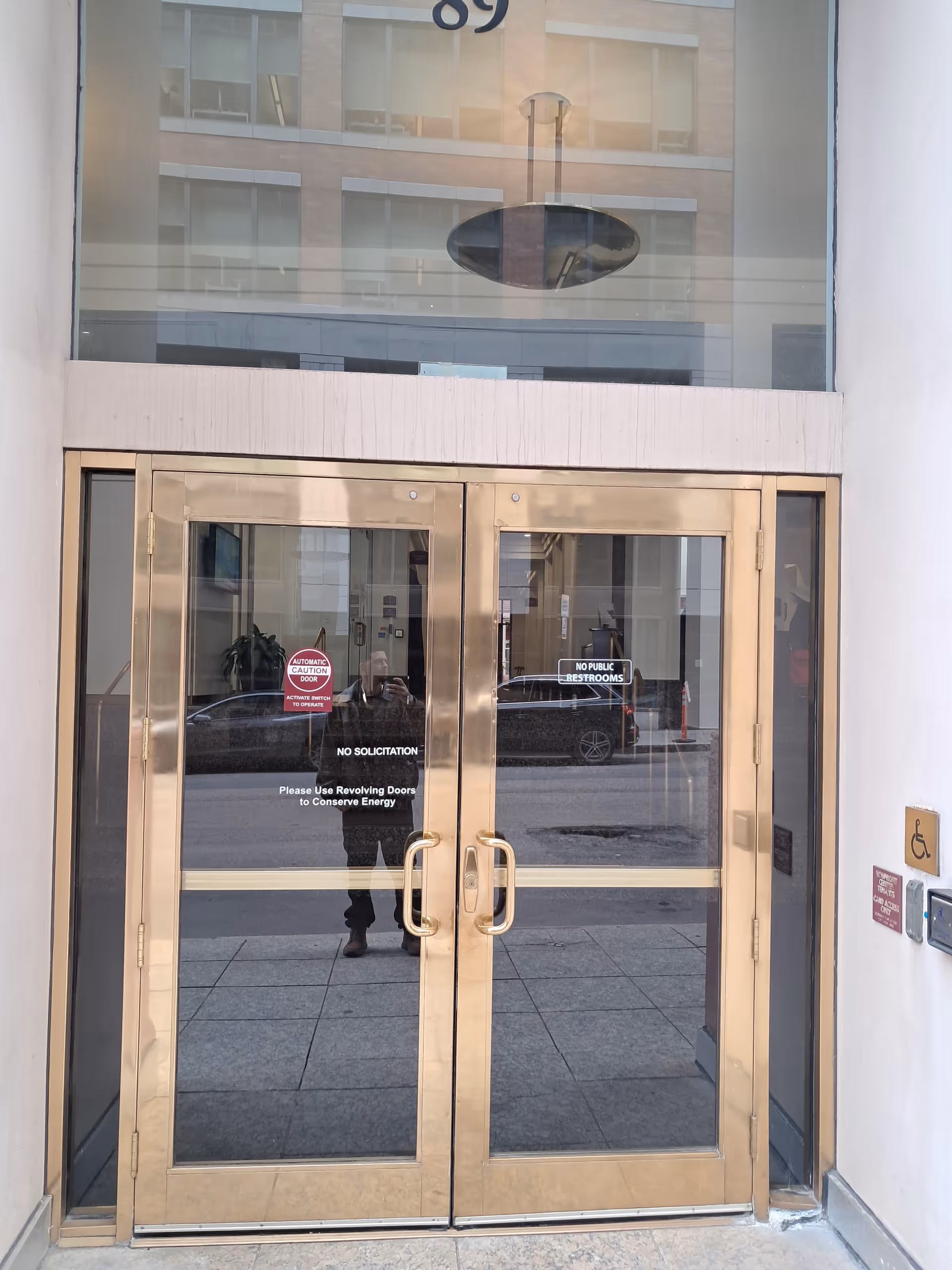 Gold-colored glass double doors at a building entrance with street reflections.