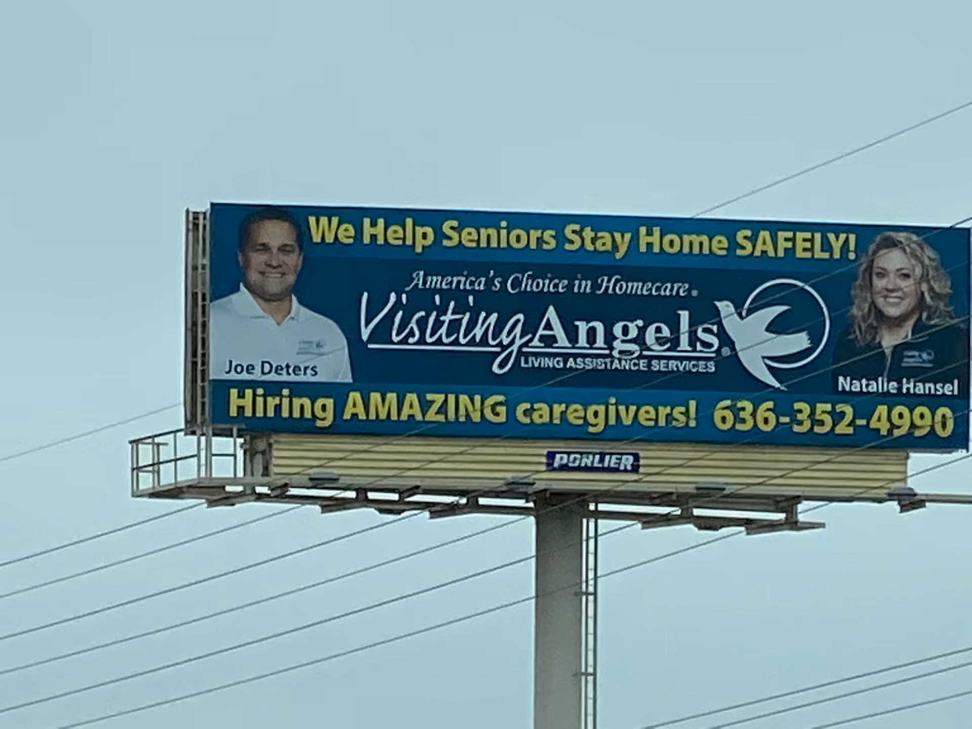 Outdoor blue billboard advertising Visiting Angels Senior Home Care on a tall pole.