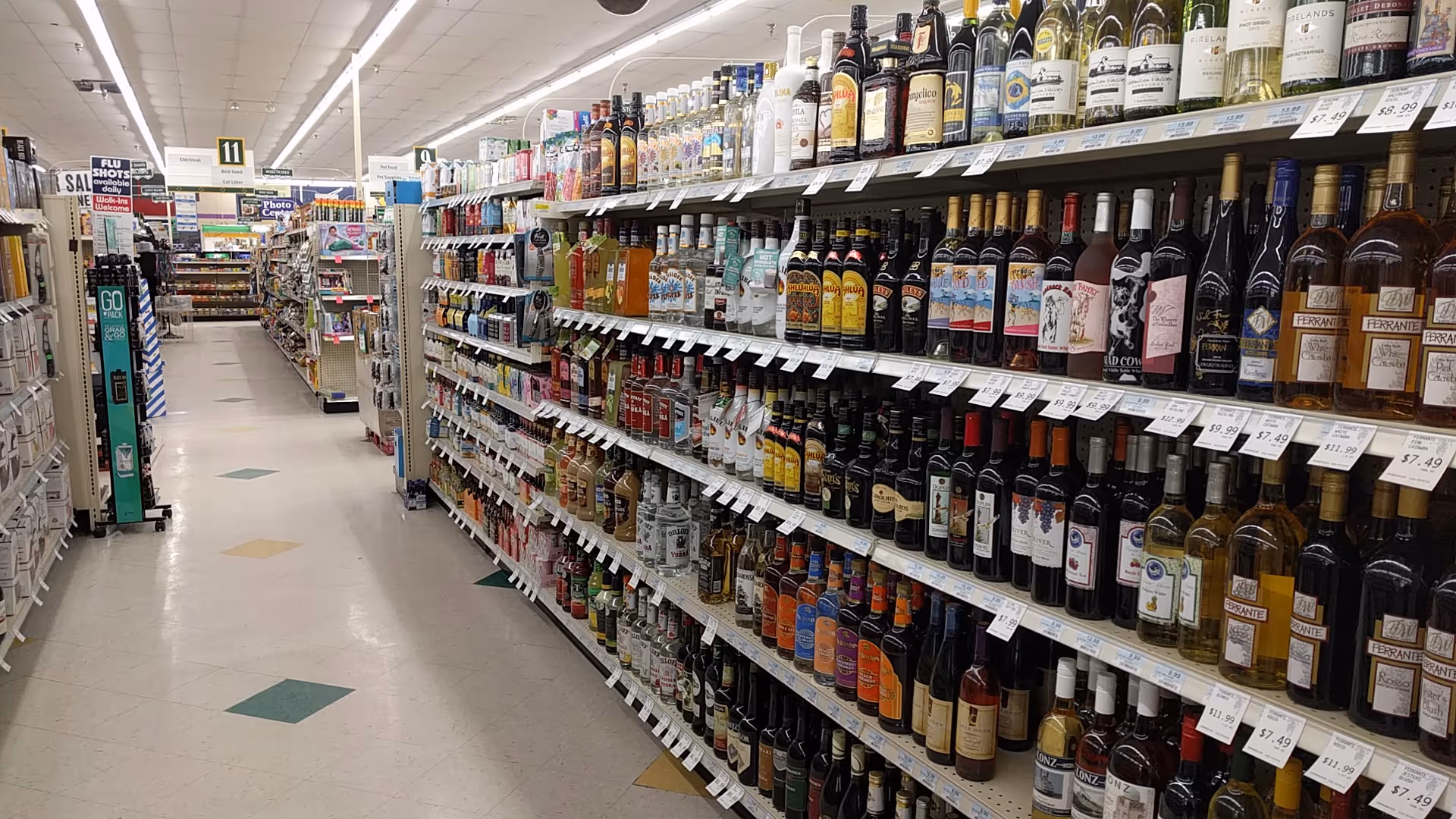 A drugstore aisle filled with shelves of bottled wines and spirits.