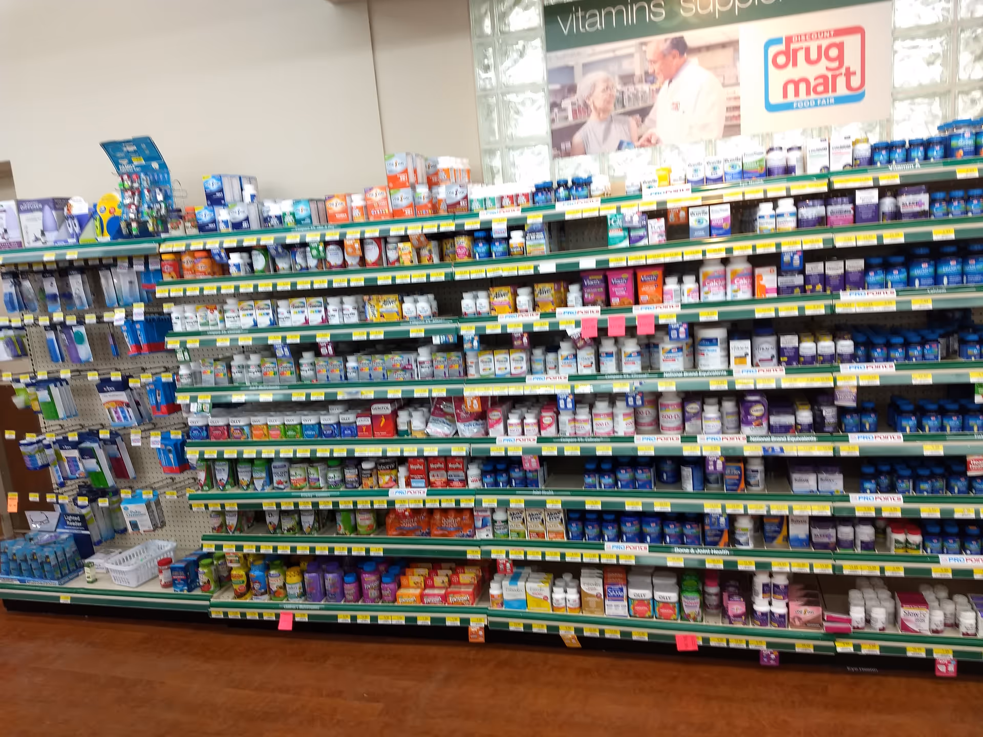 Inside Discount Drug Mart, a long aisle stocked with vitamins and medications.