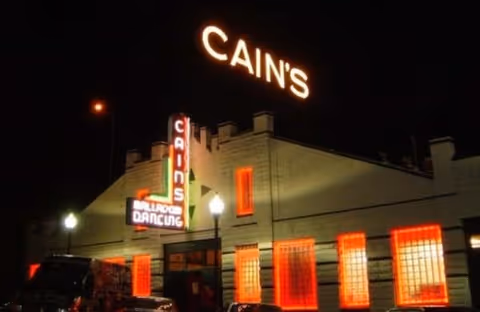 Night exterior of Cain's Ballroom with illuminated red windows and signs.