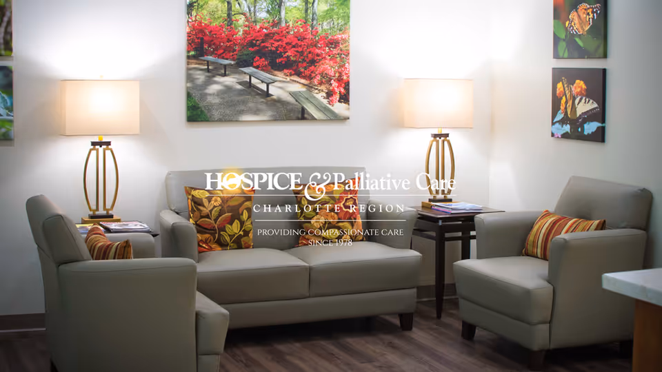 A cozy, modern lounge area with cream couches, lamps, and wall art in a senior facility.