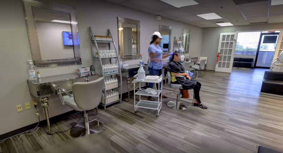Salon area in a senior facility with chairs, mirrors, and staff assisting a resident.