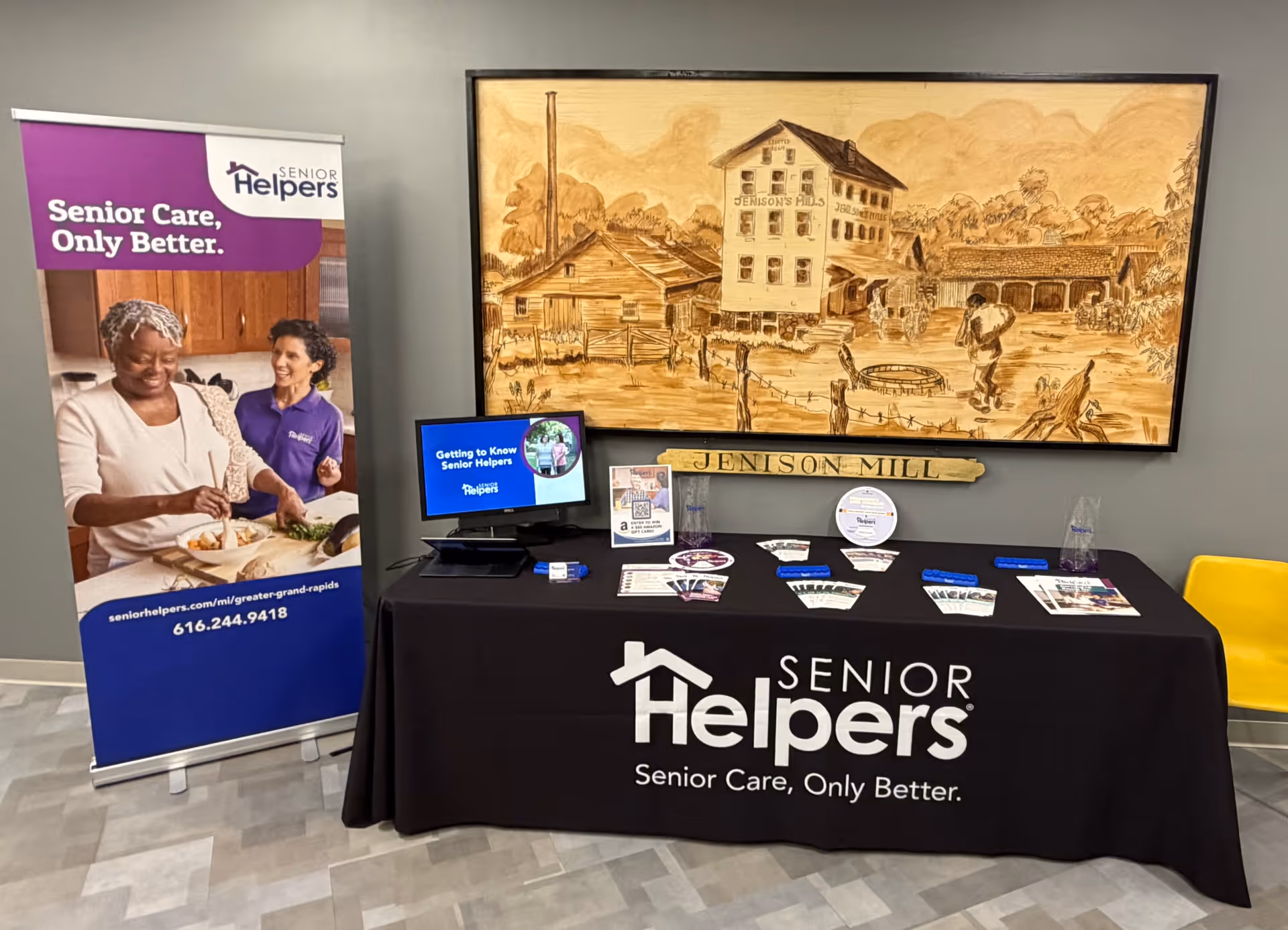 Indoor promotional display for Senior Helpers with banner, brochures, monitor, and wall mural.