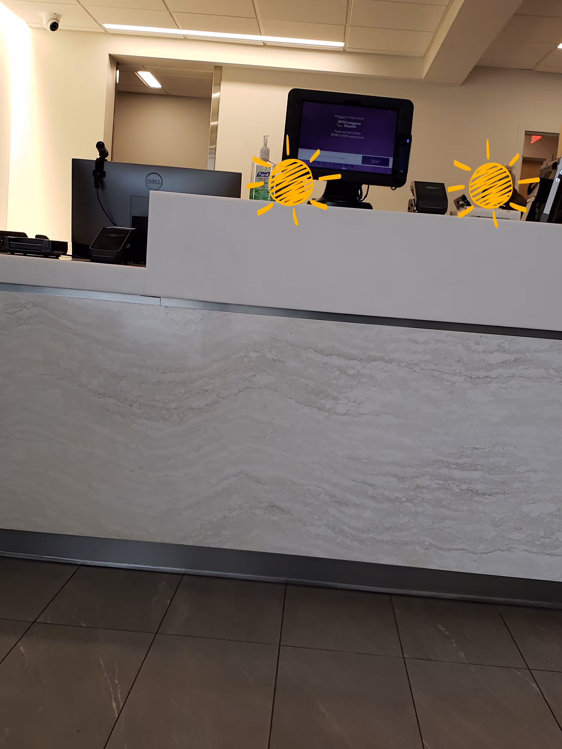 Interior of a reception area with a marble-front counter and computer monitors.