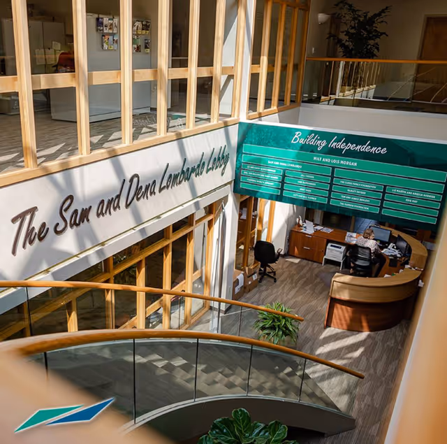Interior lobby of United Disabilities Services with reception desk and green Building Independence sign.