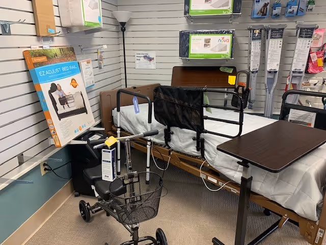A hospital-style bed with rails, a walker, and a small table in a patient room.