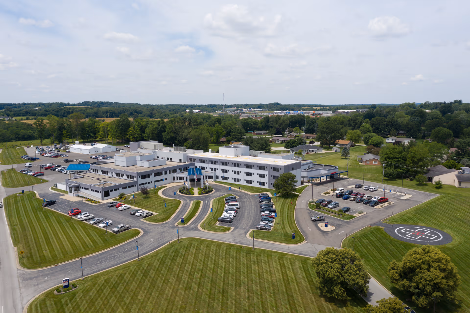 Aerial view of Highland District Hospital with curved driveways, parking lots, and green fields.