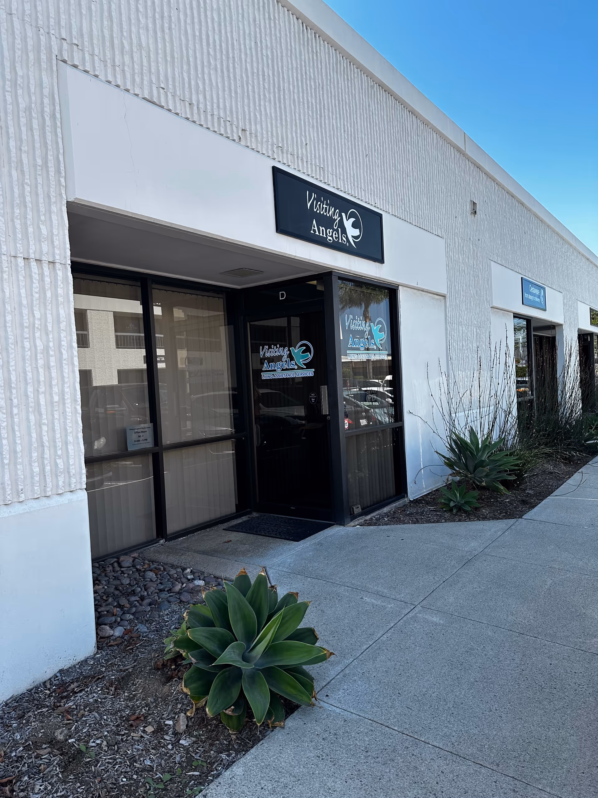Exterior of Visiting Angels facility with glass entry doors and desert landscaping.
