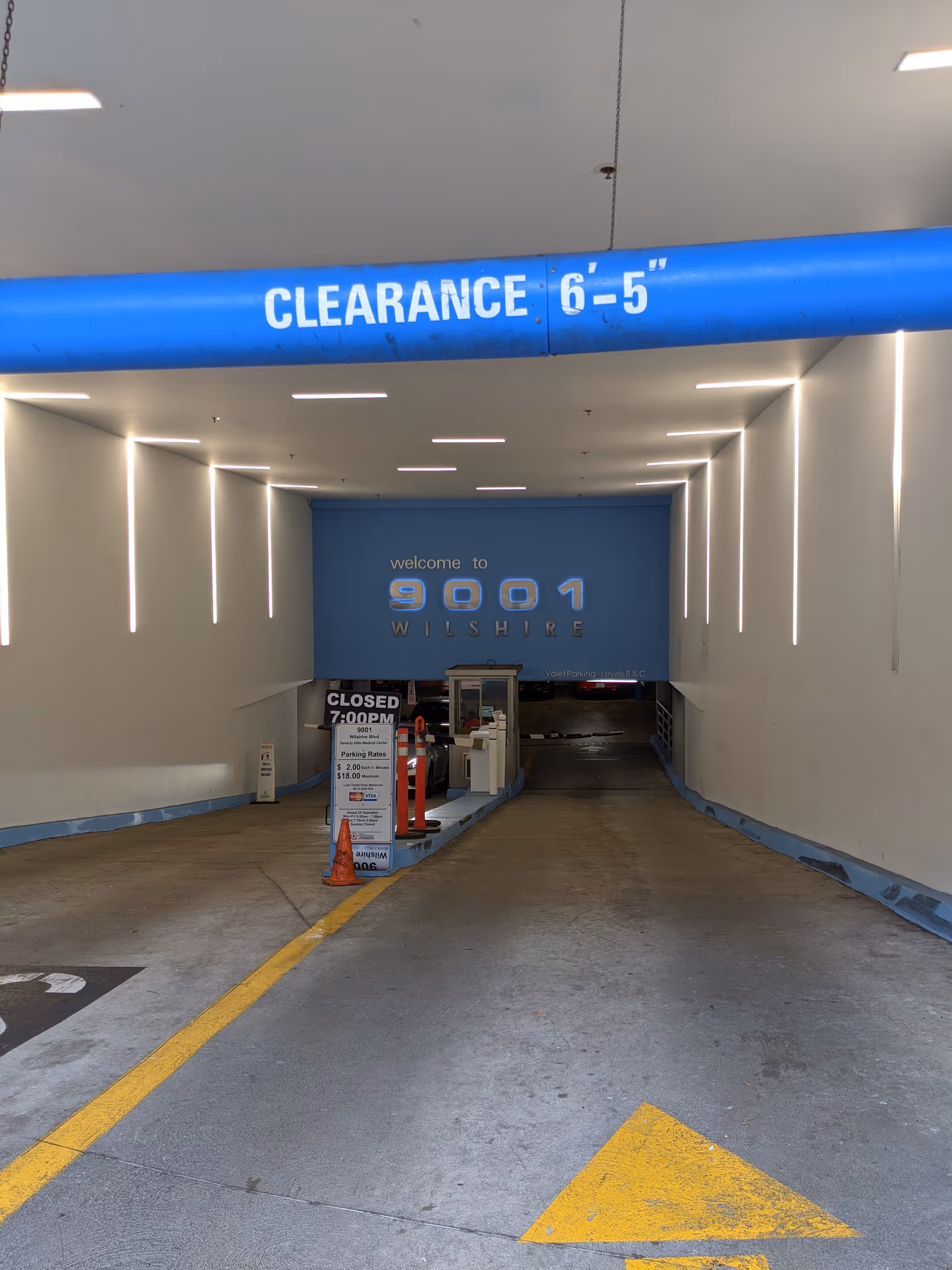 An underground ramp into a medical facility with a blue clearance sign overhead.