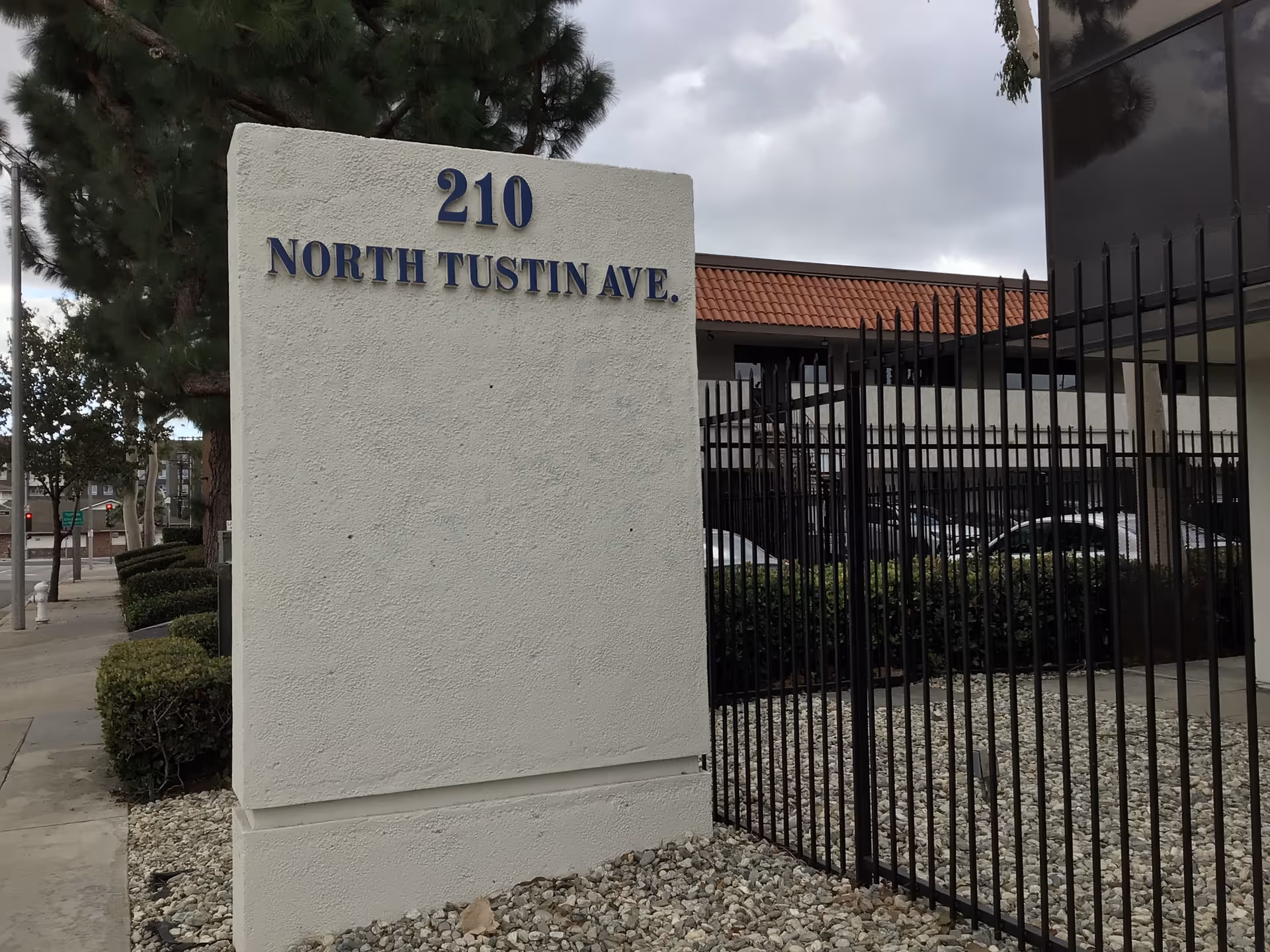 Exterior view of a building front with a large sign reading 210 North Tustin Ave.