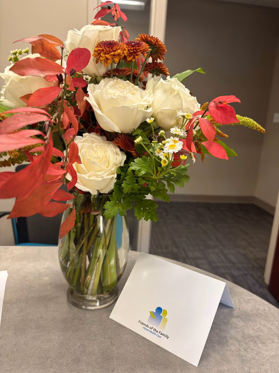 Colorful floral arrangement in a vase on a reception counter in a facility hallway.
