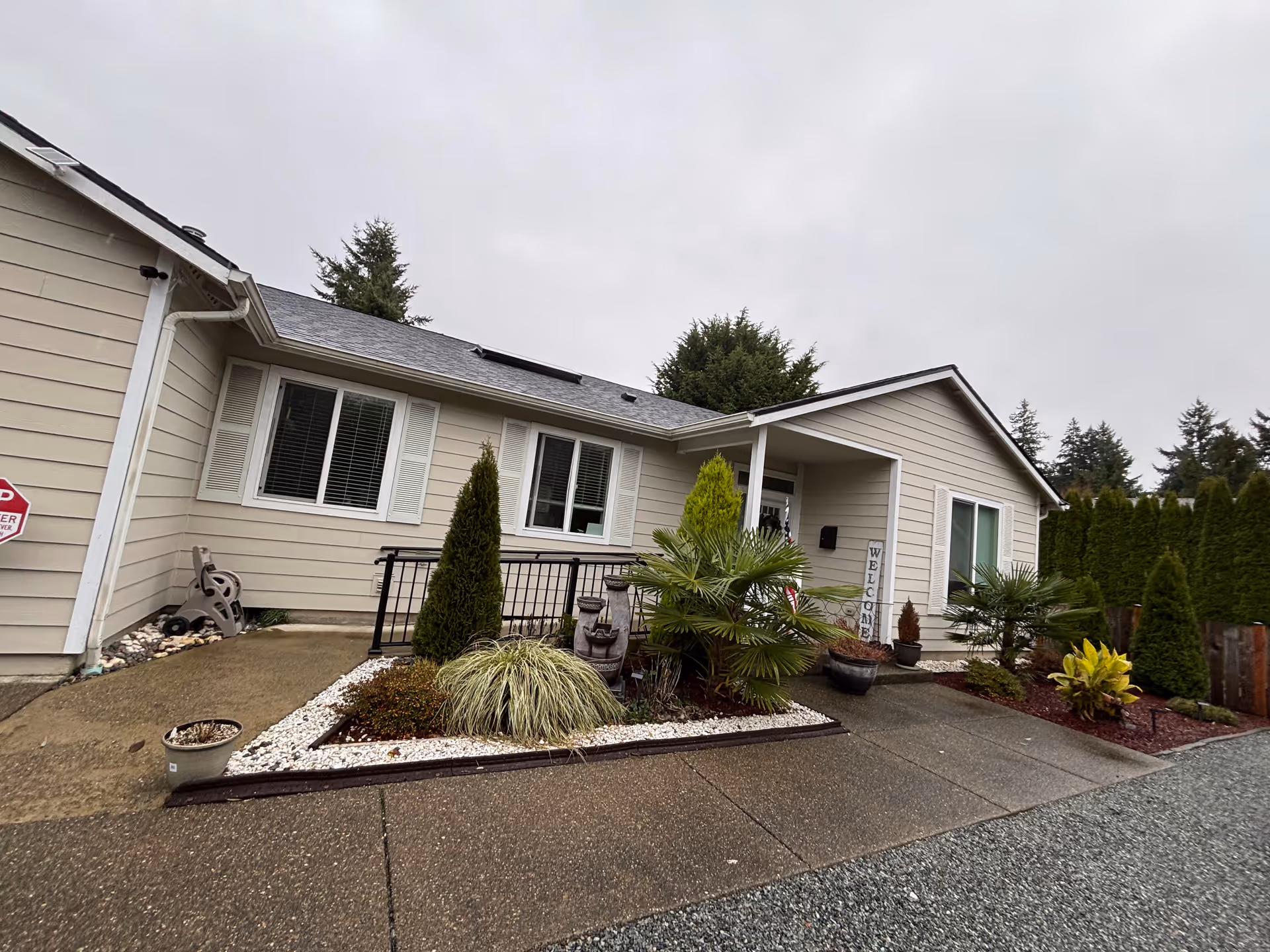 Single-story beige building exterior with a small landscaped front yard and welcome sign.