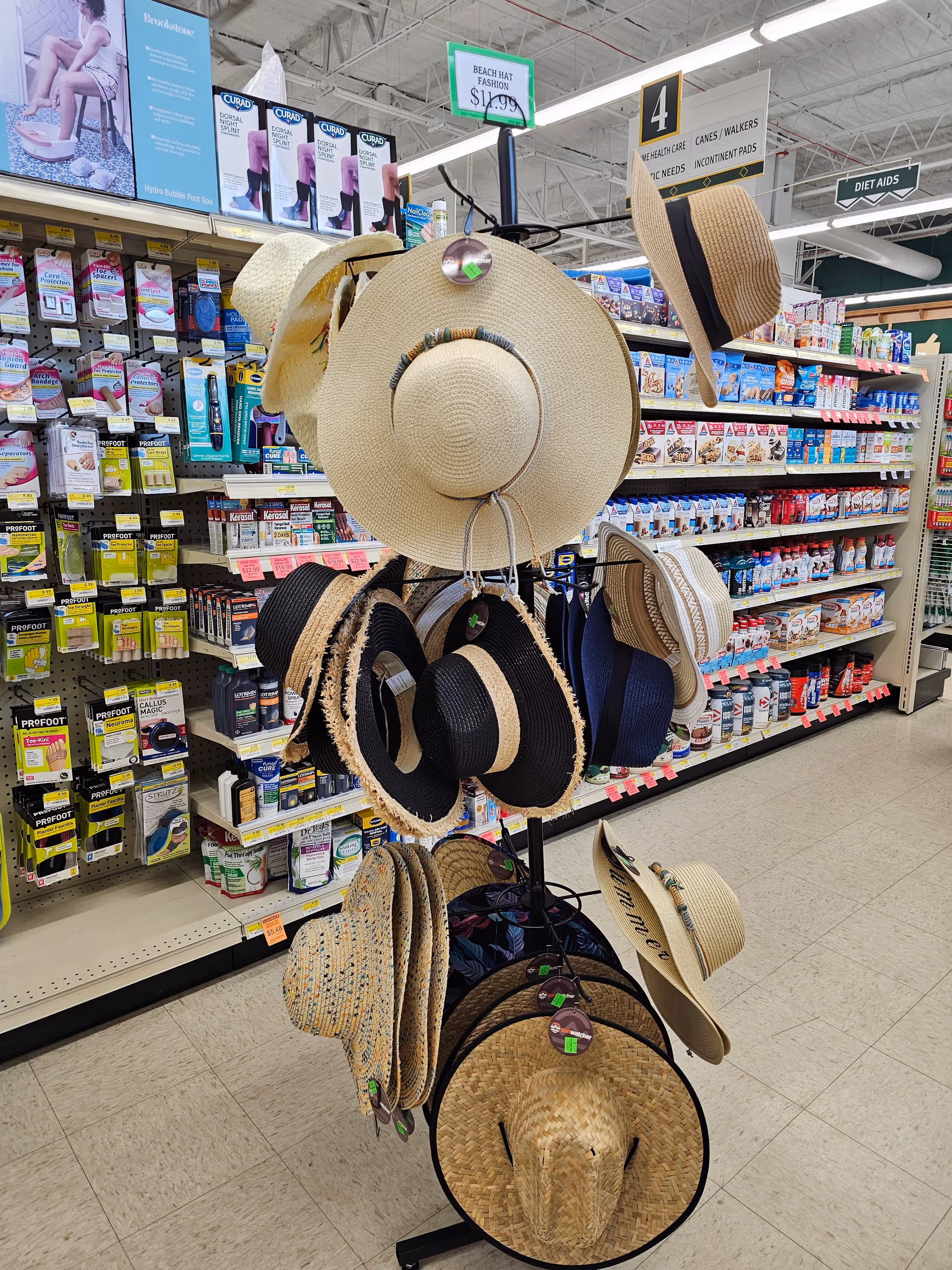 A hat display with various sun hats on a rotating stand in a store aisle.