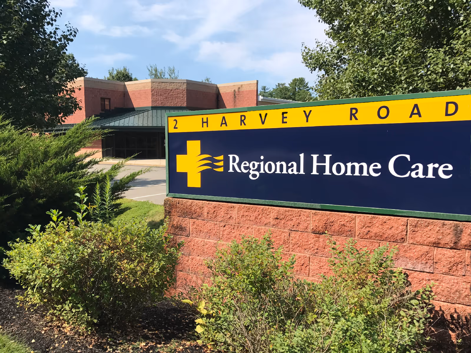 Regional Home Care sign on brick wall with greenery and a building behind.