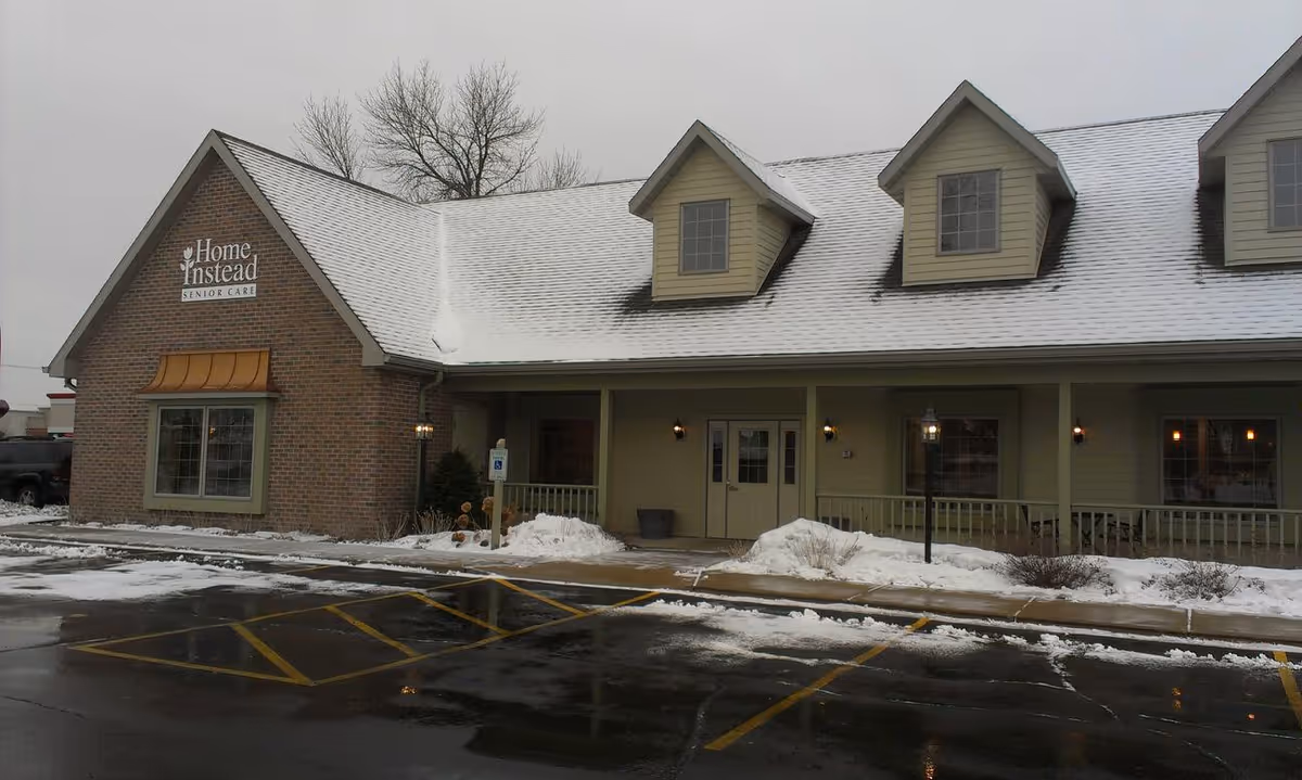 Snowy exterior of a Home Instead Senior Care building with front entrance and parking lot.