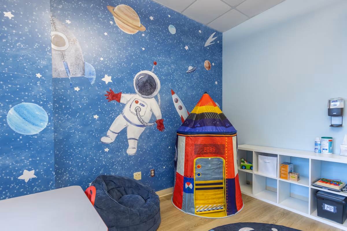 Interior play area with space-themed mural, rocket tent, and shelves