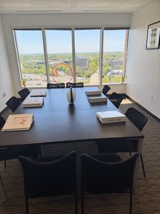 Interior conference room with a large table, multiple chairs, and a city view.
