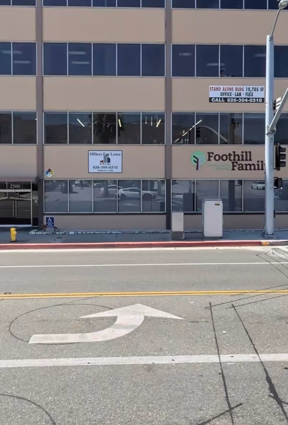 Beige glass-front office building facade with Foothill Family sign along a city street