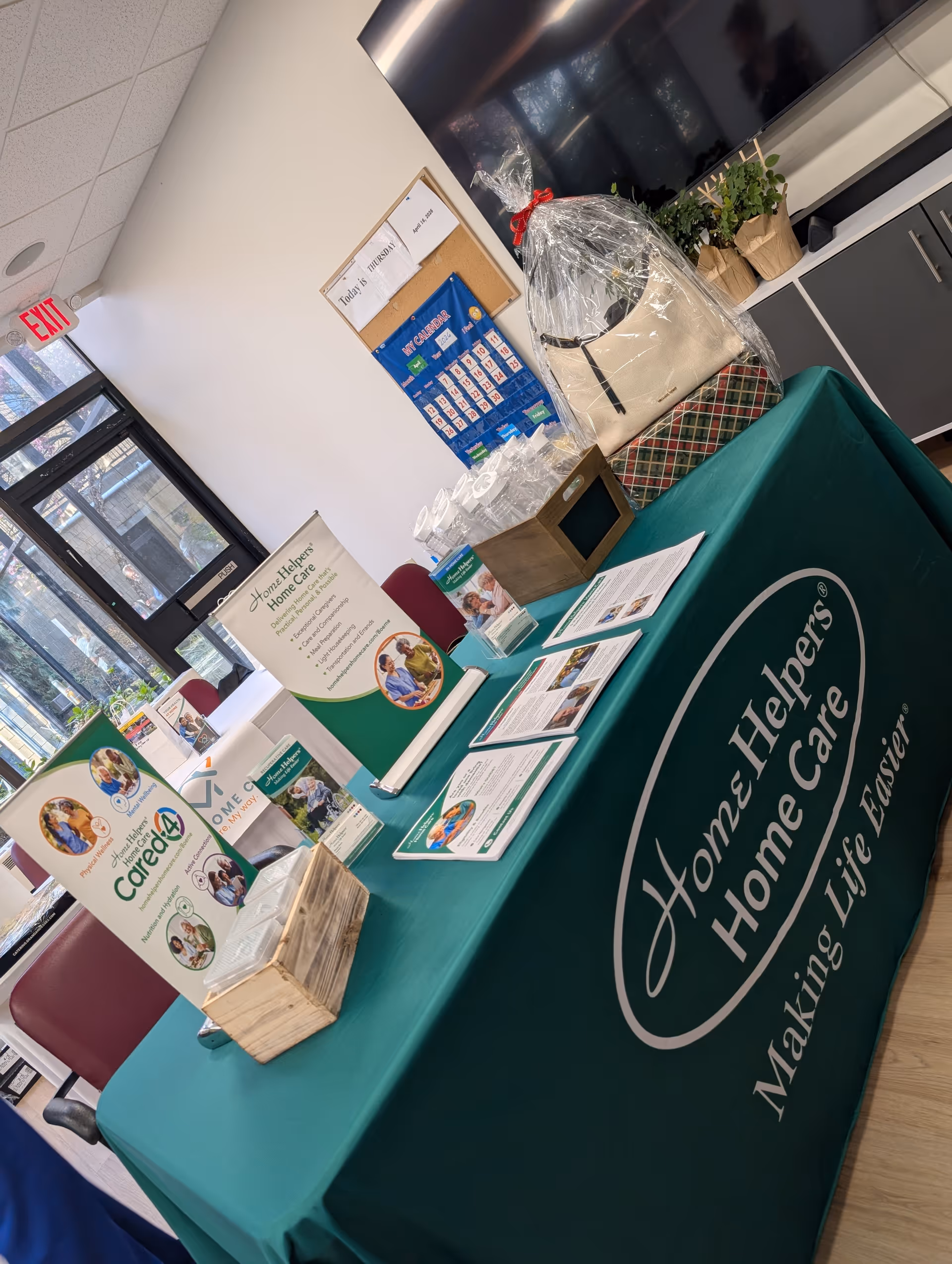 Promotional display table for Home Helpers Home Care inside a bright facility lobby.