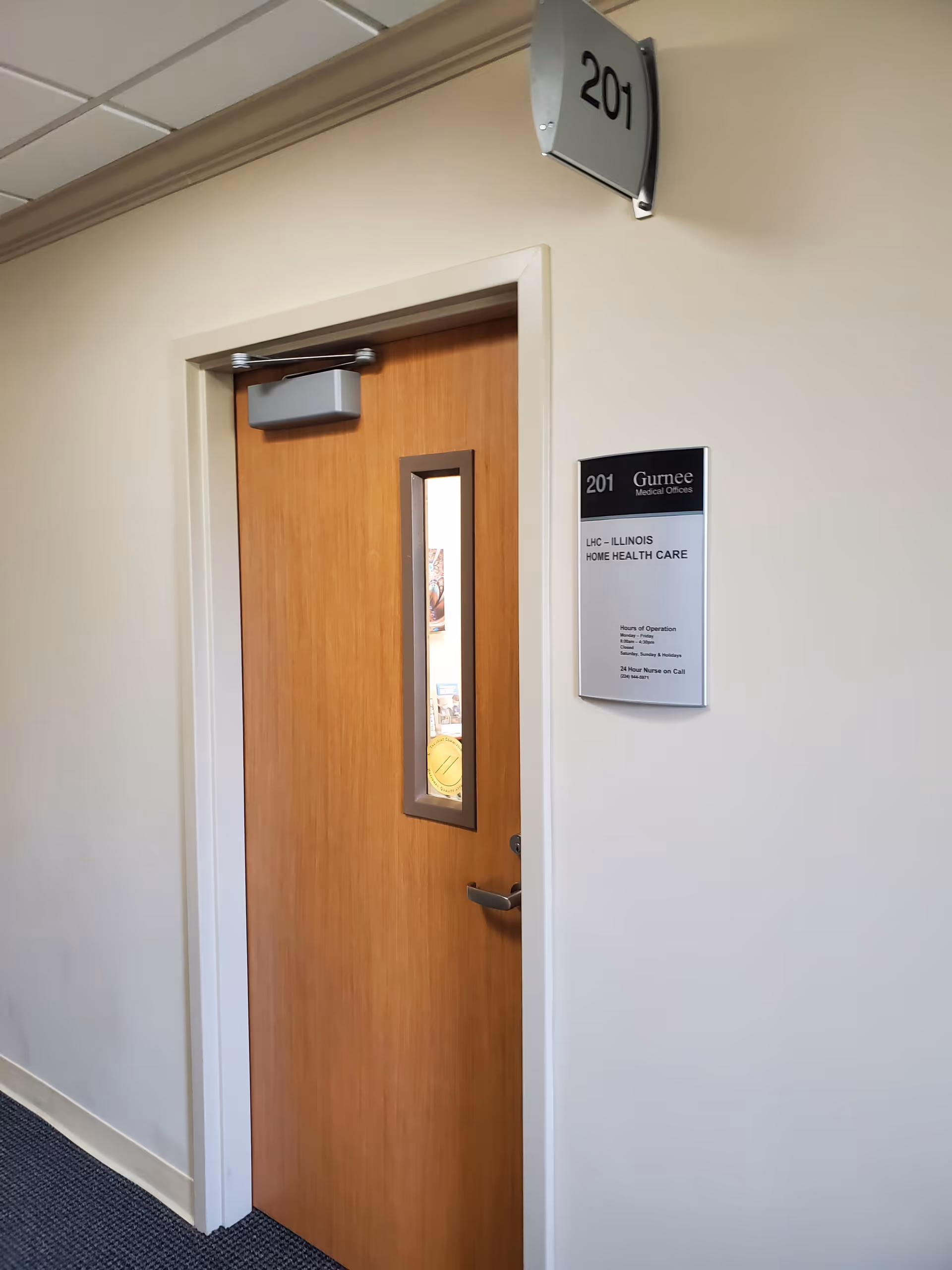 Wooden door labeled 201 in a hallway of a senior care facility.