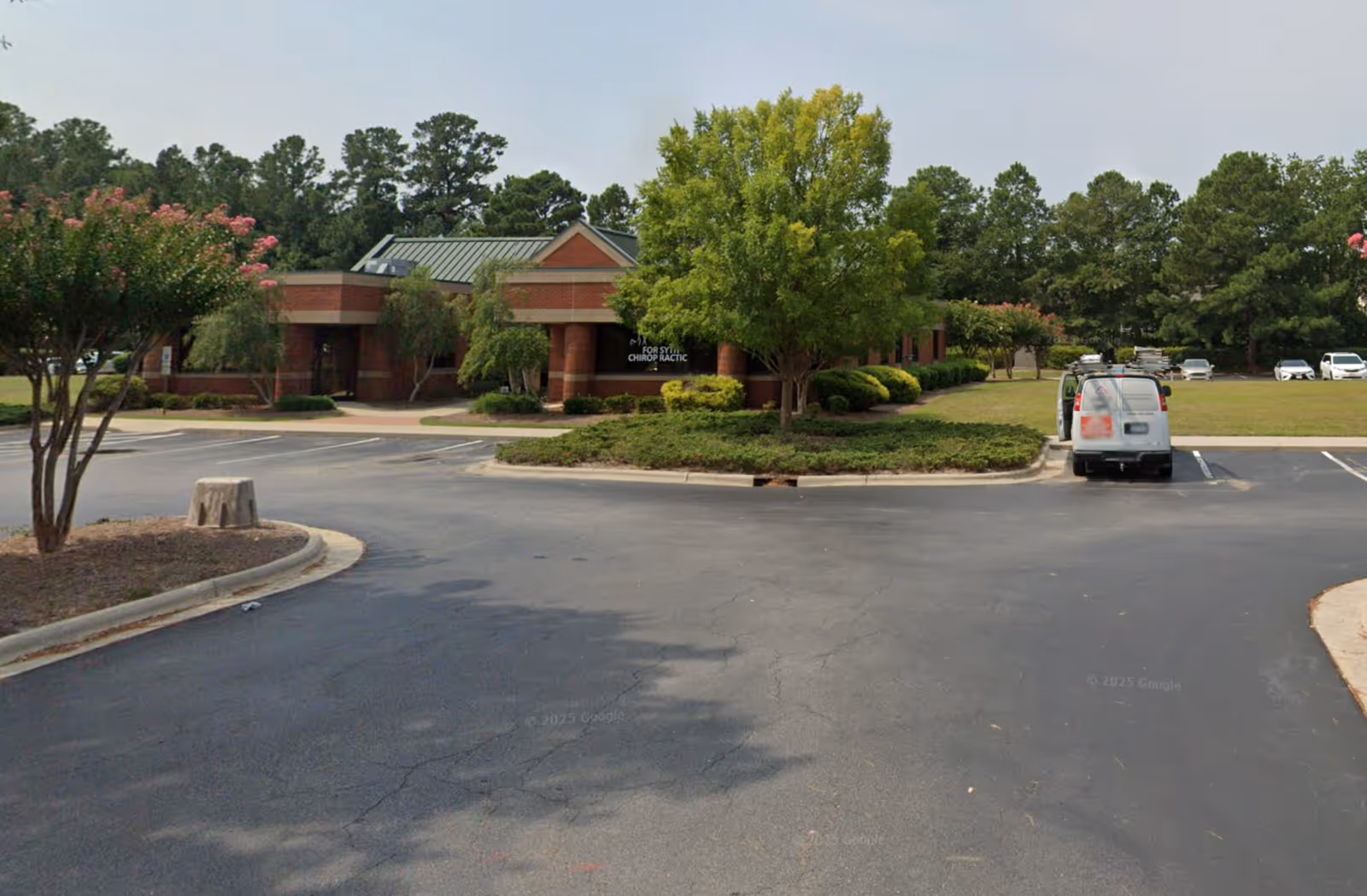 Exterior view of a brick senior living facility with parking, trees, and landscaping.