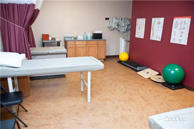 Therapy room with treatment table, exercise equipment, and medical supplies.