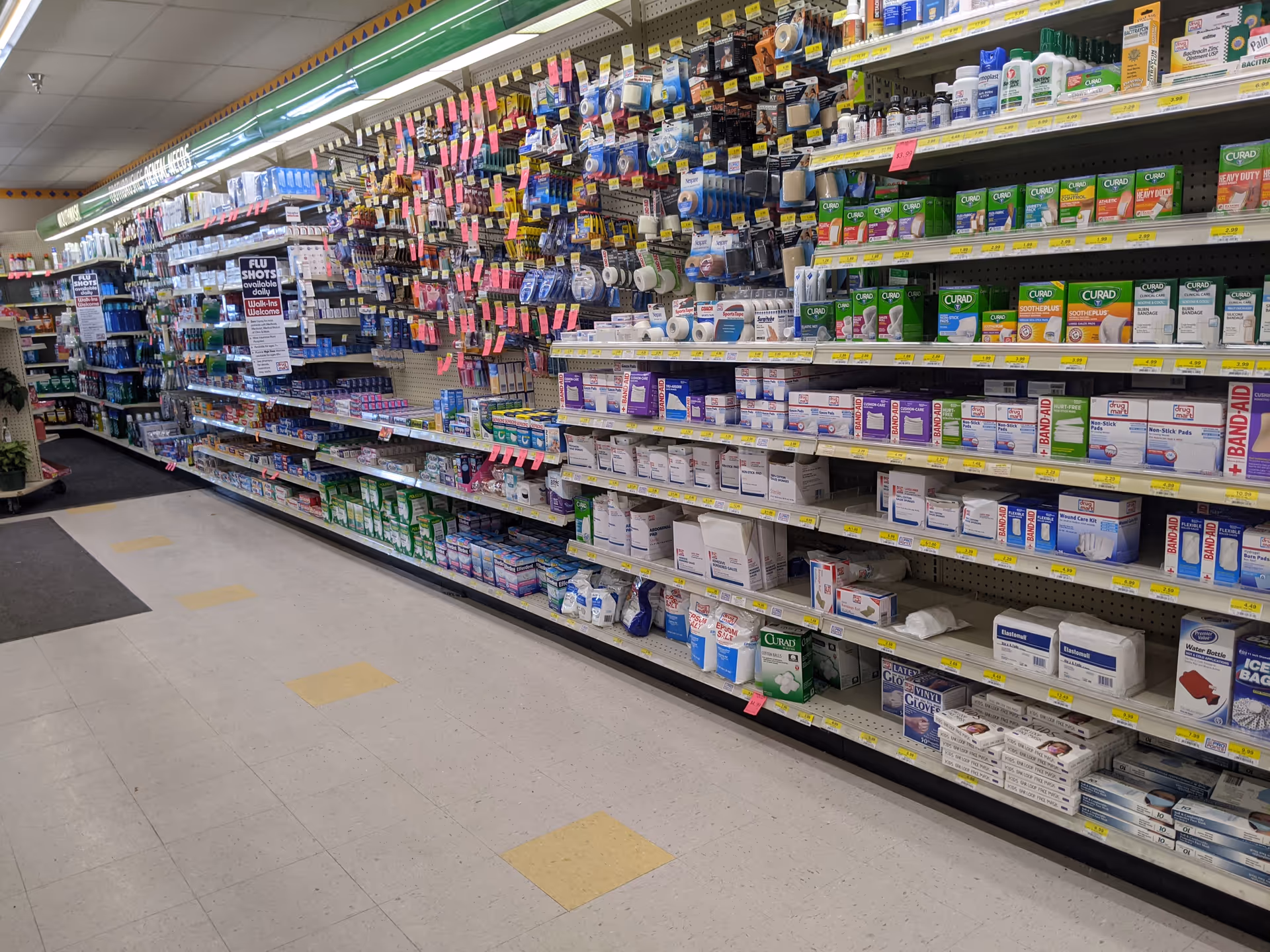 A long store aisle with shelves full of medications and supplies.