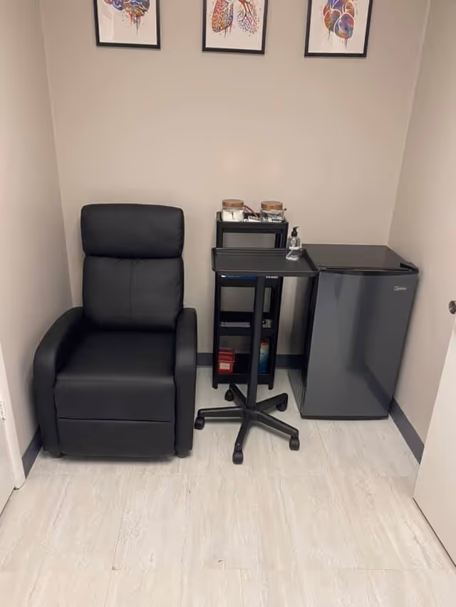 Small interior corner with a black leather recliner, a rolling cart, and a mini-fridge.