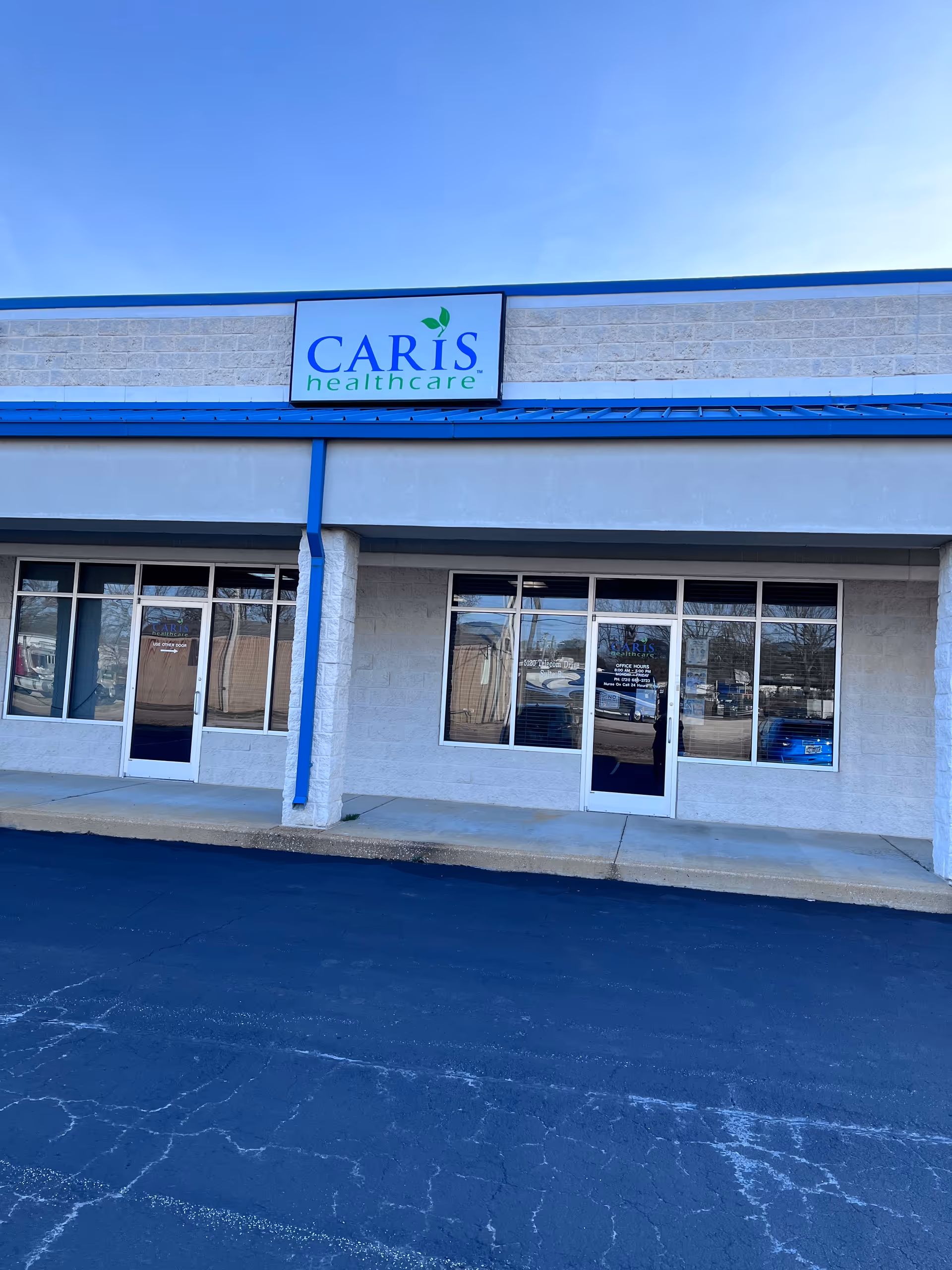 The Caris Healthcare storefront exterior with glass doors and blue trim.