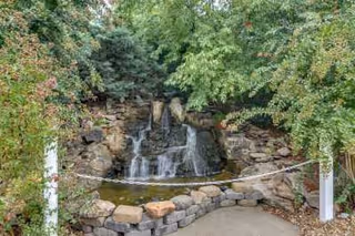 Stone waterfall cascade surrounded by rocks and lush trees in a tranquil garden.