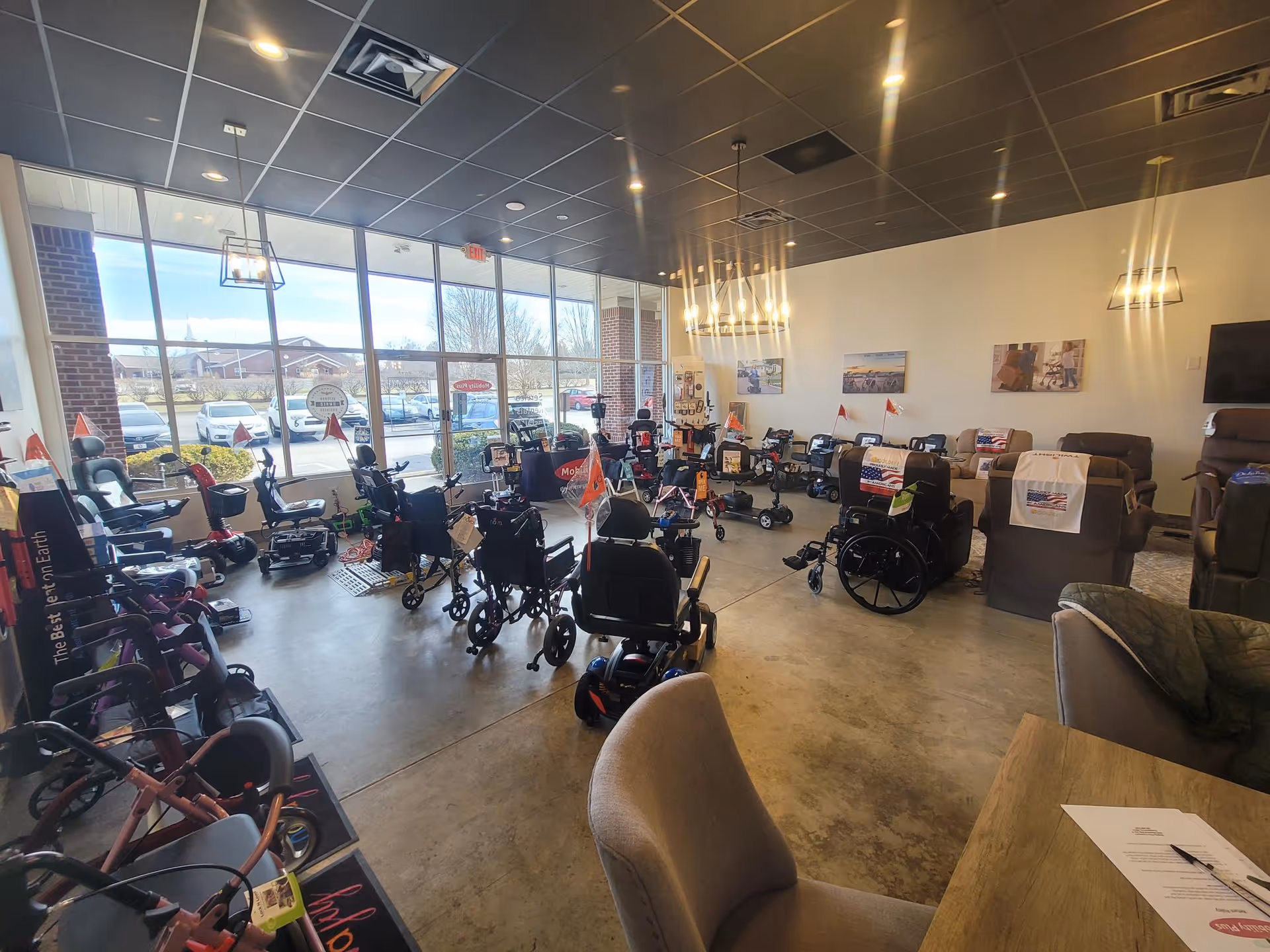 Indoor showroom displaying many mobility scooters and wheelchairs near large windows.