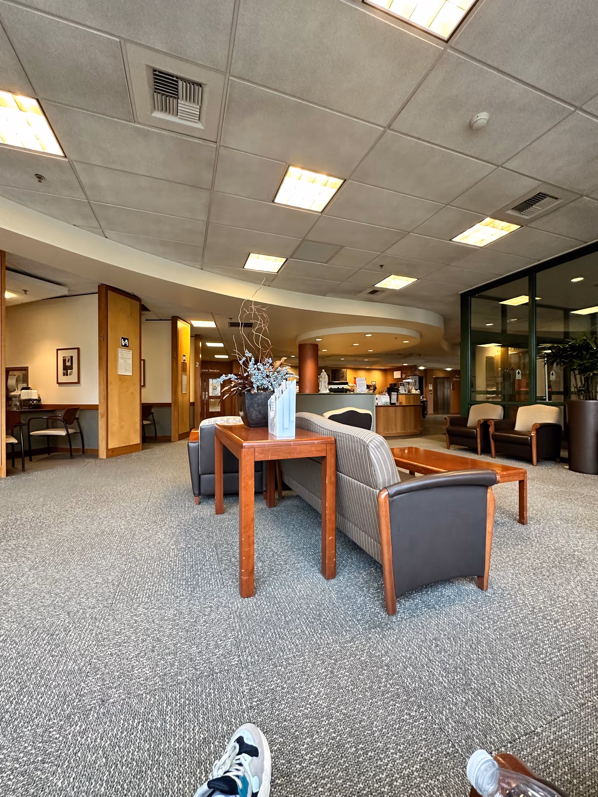 Interior lobby of a senior living facility with couches, tables, and a reception desk in background.