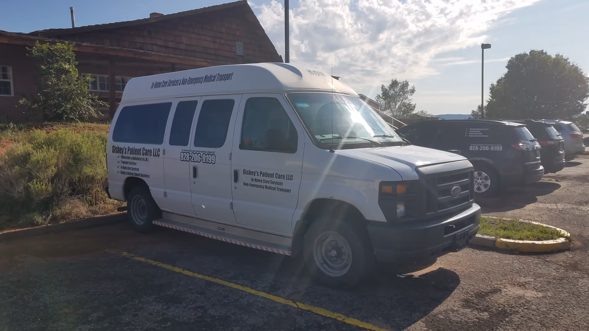 White van labeled Gishey's Patient Care parked in a lot beside a building.