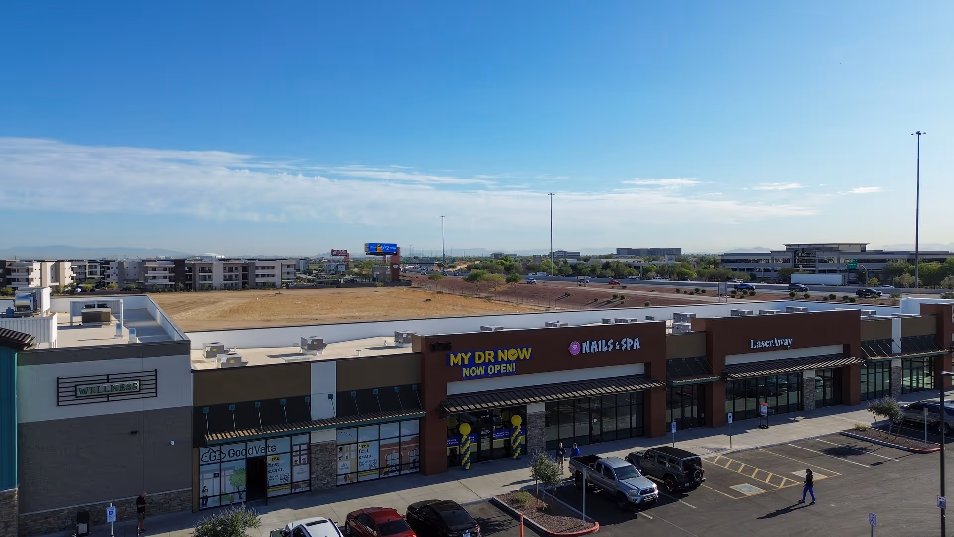 Aerial view of a strip mall exterior featuring MY DR NOW storefront and parking lot.