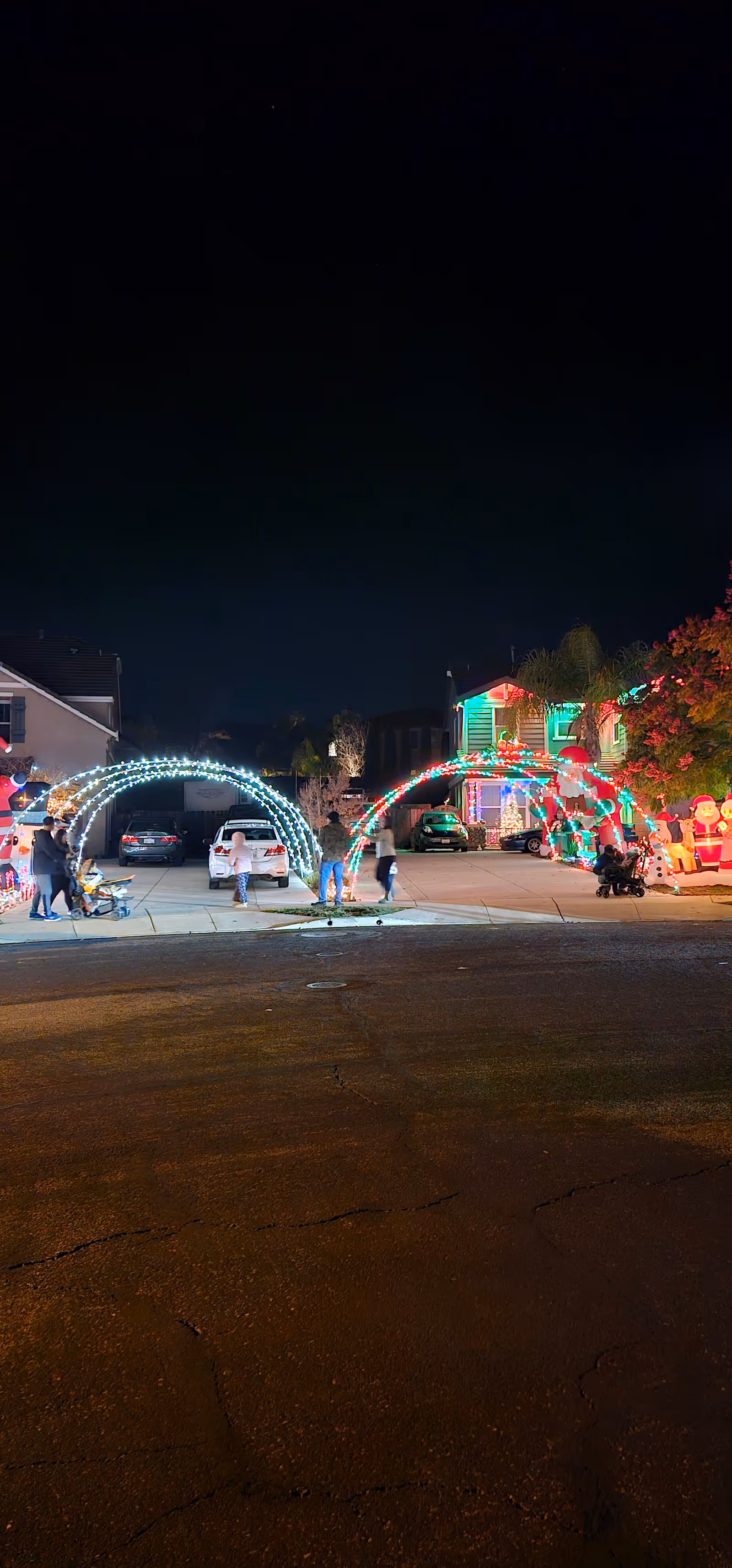 Nighttime exterior street scene with illuminated arches and festive holiday lights.