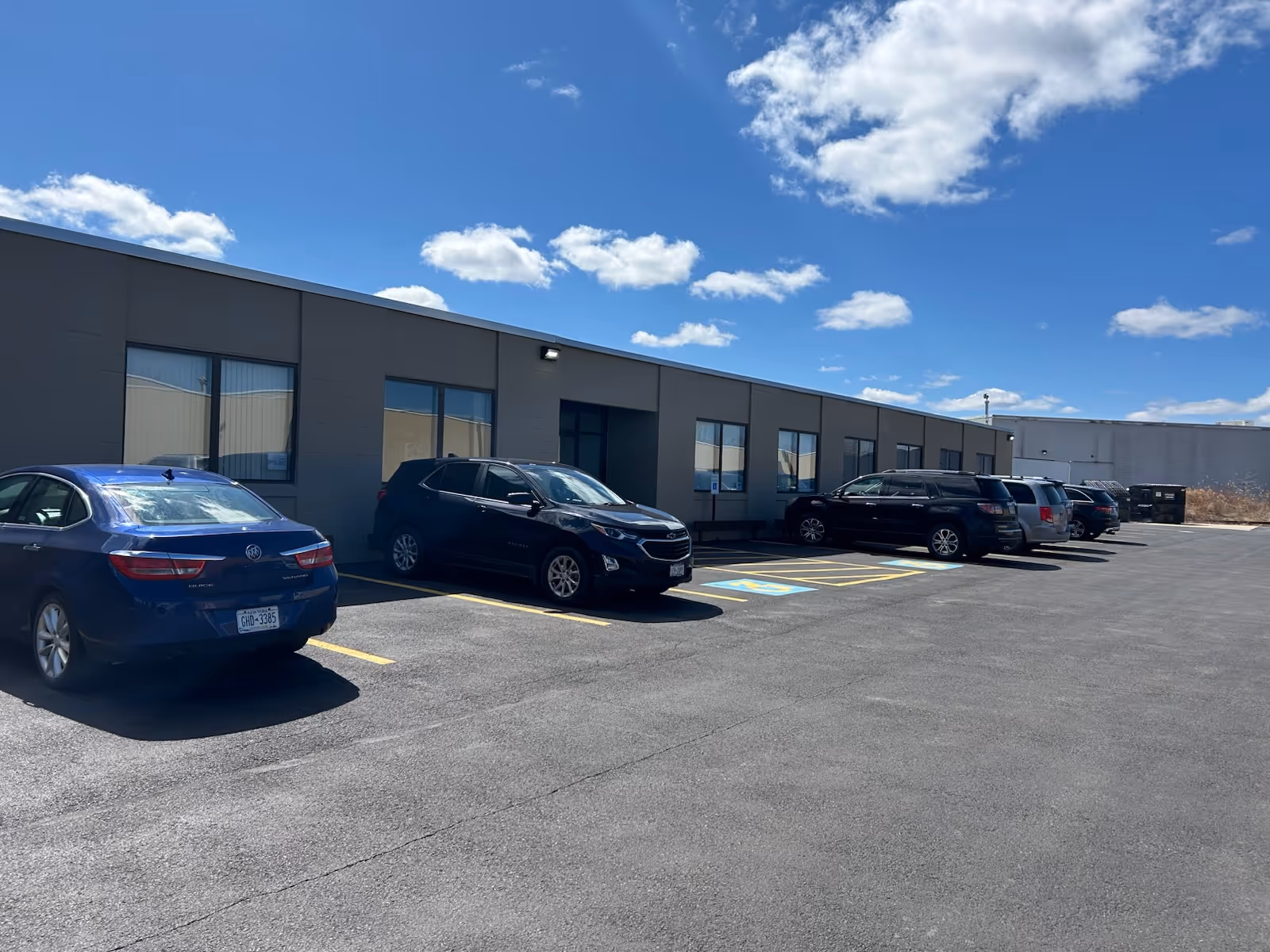 Exterior view of a Home Instead facility with several parked cars in the lot
