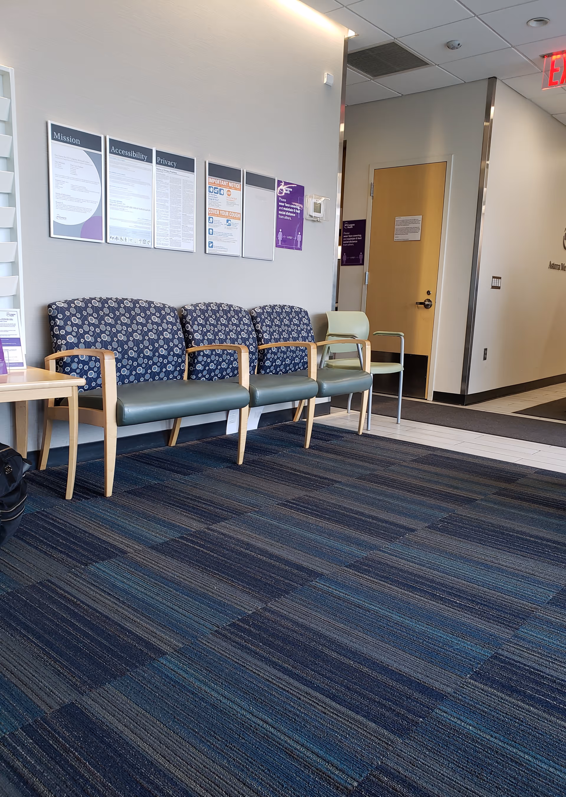Waiting area with blue patterned chairs and wall posters at NYU Langone Astoria.