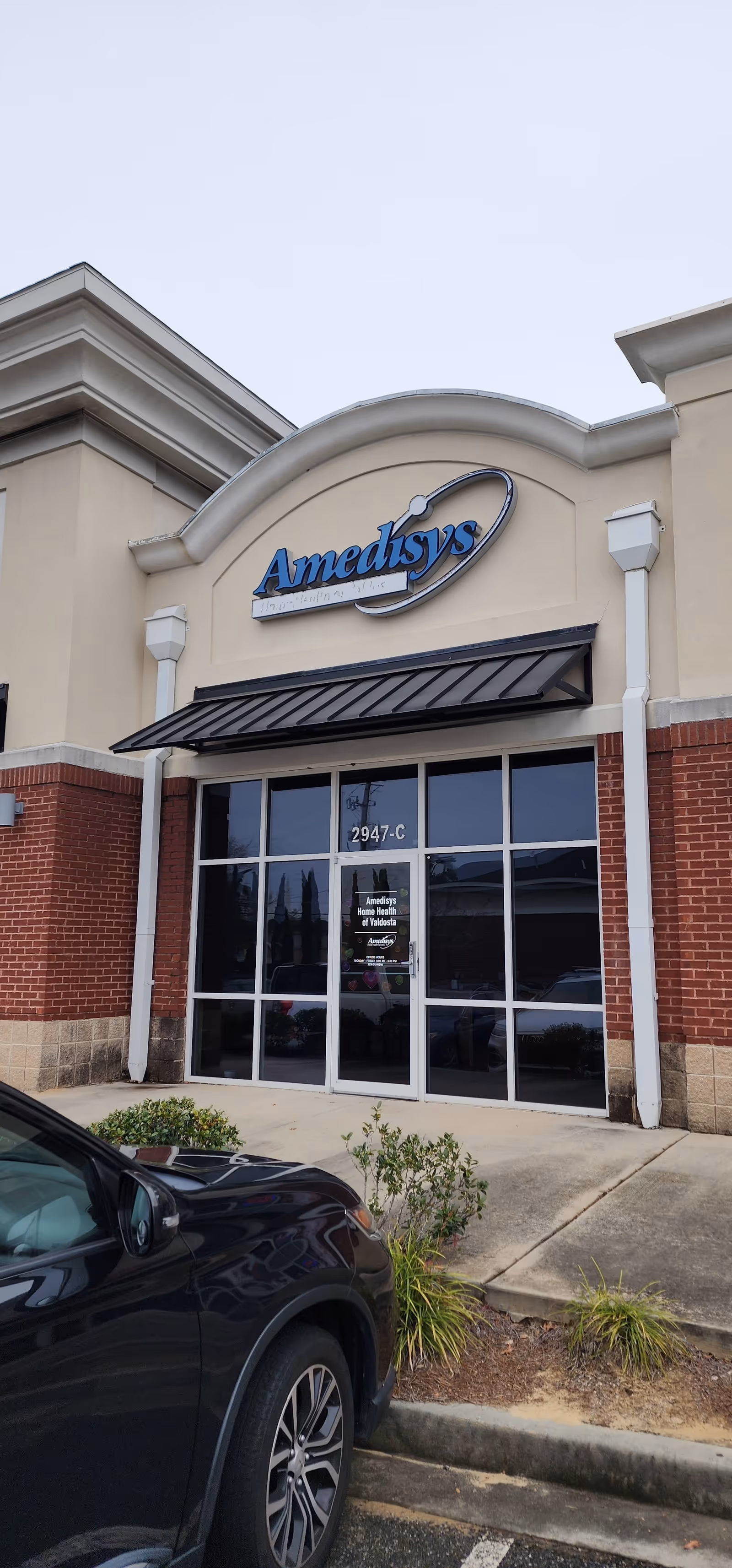 Amedisys Home Health Care storefront entrance with glass doors on a tan brick facade
