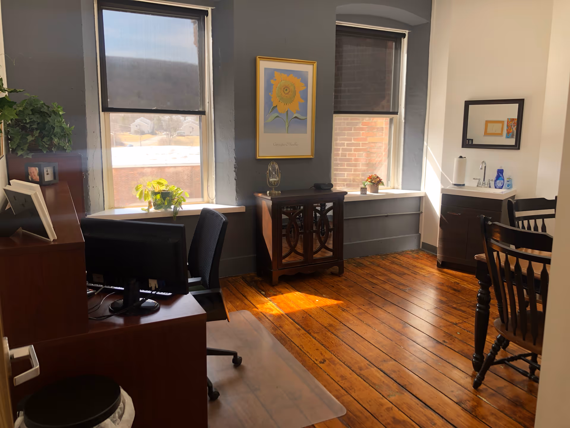 Office-like room in a senior living facility with desks, chairs, plants, and windows.