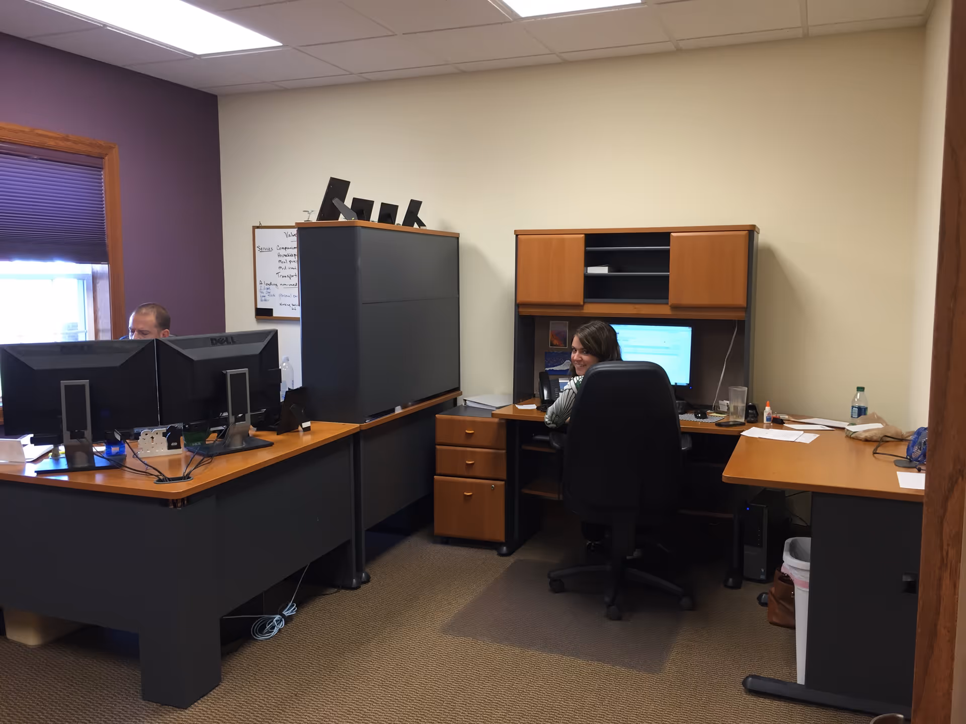 Office interior with staff at desks, computers, and filing cabinets.