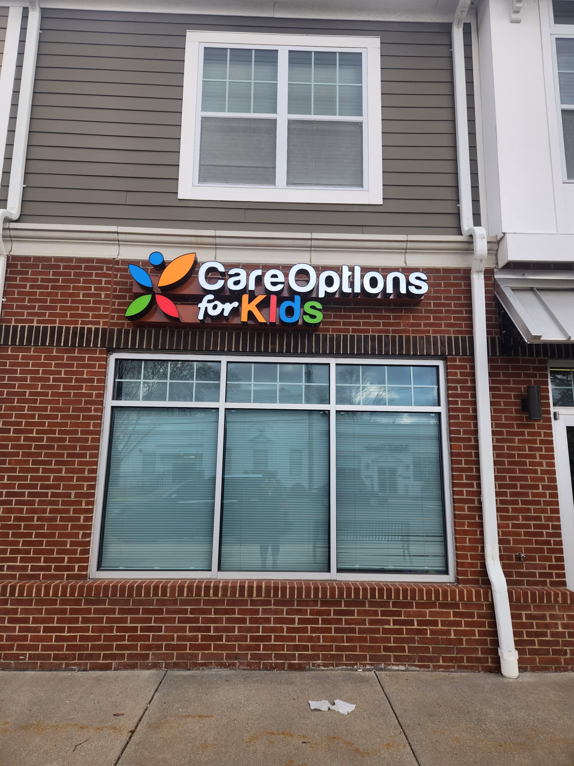Exterior view of a brick building with a colorful CareOptions for Kids sign.
