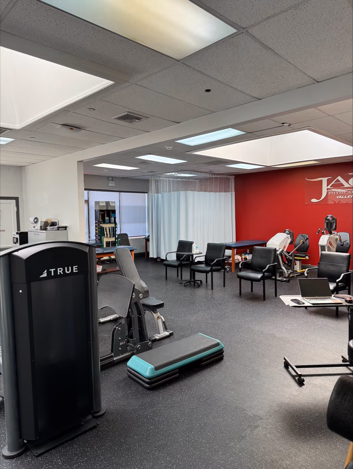 Interior gym at JAG Physical Therapy with exercise equipment and chairs.