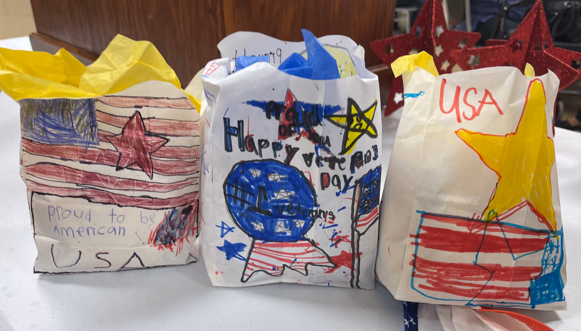 Three decorated paper bags with patriotic drawings on a table.