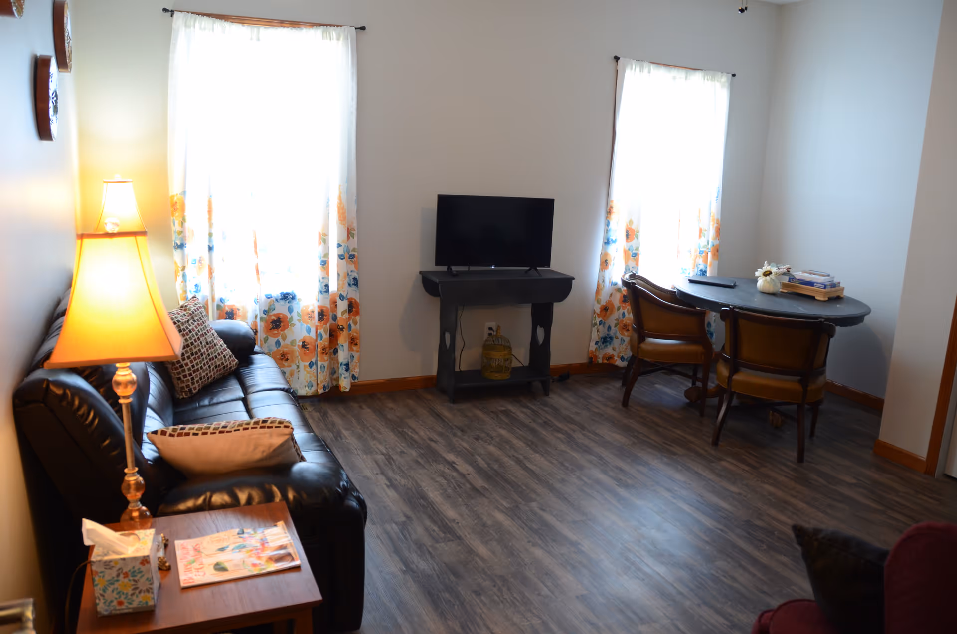 Cozy living room with sofa, TV, and dining table in a senior facility.