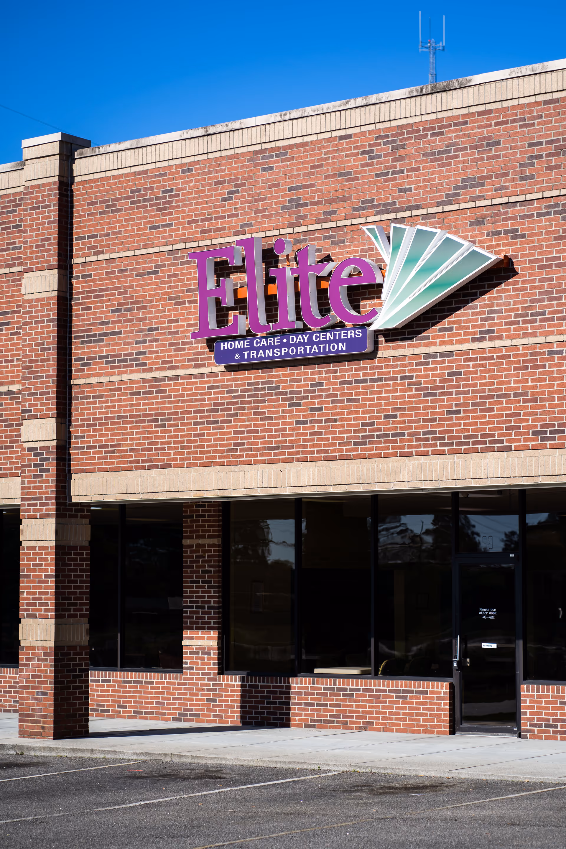 Brick exterior of Elite facility with a large purple sign above the glass entrance.